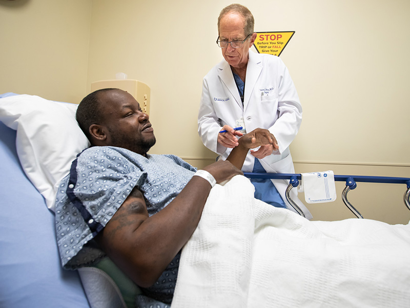 Dr. James Wynn, professor of transplant surgery, checks in with patient Harry Miggins shortly before Miggins' outpatient procedure.