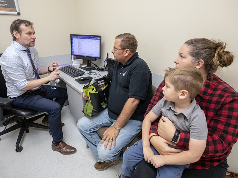 Dr. Franco Cabeza Rivera, left, chats with Matt Richmond during a follow-up appointment to Richmond's June 20 kidney transplant. Also pictured are Richmond's wife, Krystal, who donated the kidney, and their son Morgan, 4.