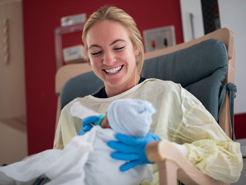 UMMC nursing student Corryl Kemp feeds a NICU patient breast milk by bottle.