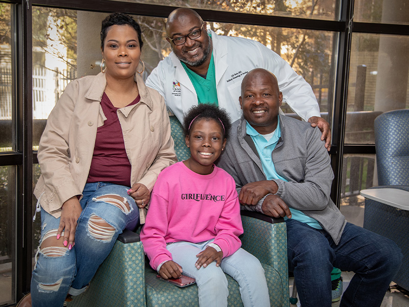 Kali Mitchell smiles with parents, Joneaset and Darold Mitchell, and hematologist/oncologist Dr. Dereck Davis.