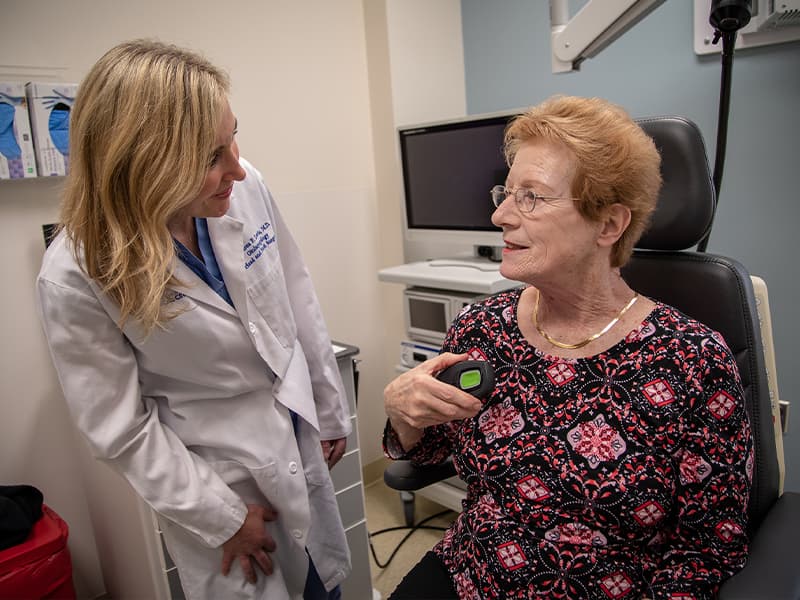 Doctor examines patient who is holding the device that helps open her airways for sleep.