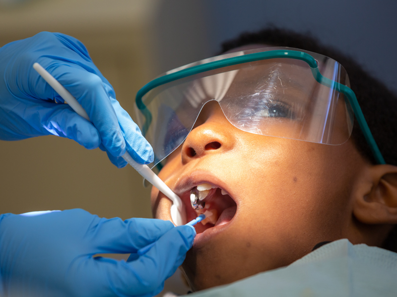 Close of up patient with dental tools in mouth.