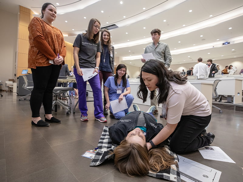 Huong Pham, foreground right, an occupational therapy student in the School of Health Related Professions, adjusts her classmate Mallory Smith's head while Smith acts as an opioid overdose victim during naloxone administration training last Friday in the medical education building. Bailey McPhail, left, a School of Pharmacy student, instructs the group that includes, from left, Elizabeth Bridges, OT student; Keely Mitchell, OT student; Sherlee Chandler, OT student; and Davis Kelly, medical student.