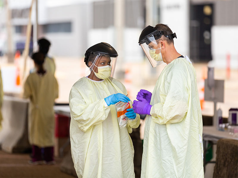 Two people standing at testing site in full PPE.