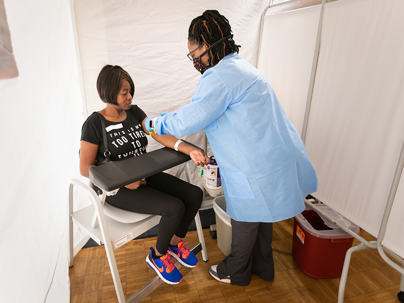 April Collier, right, phlebotomist, prepares to draw labs from Tamathy Summerall of Hattiesburg in a tent near the UMMC Cancer Center and Research Institute's outpatient clinics at the Jackson Medical Mall Thad Cochran Center.