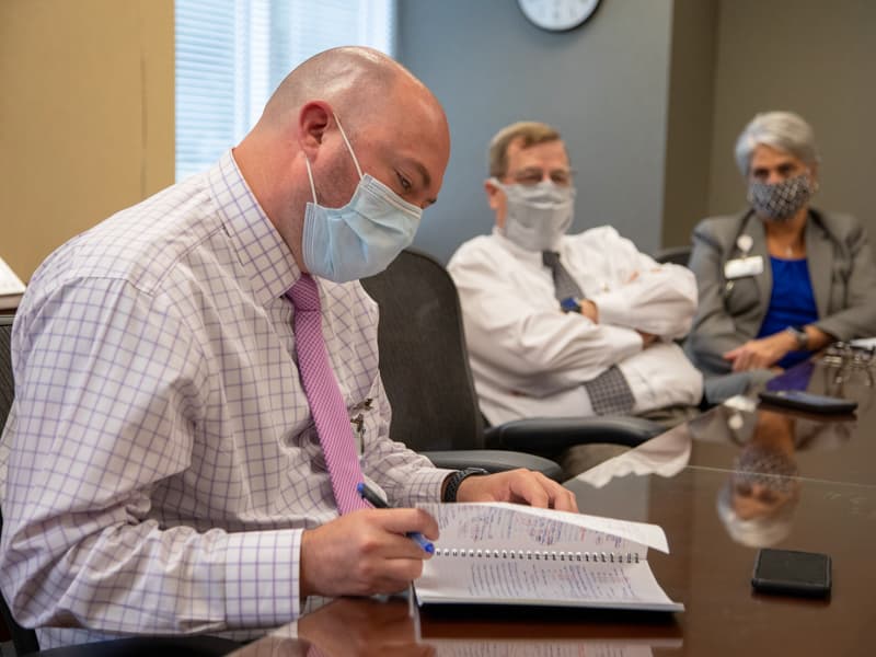 Jason Zimmerman, left, associate chief nursing officer for adult nursing services, reviews notes during the UMMC Health System weekly leadership meeting to discuss COVID-19 response.