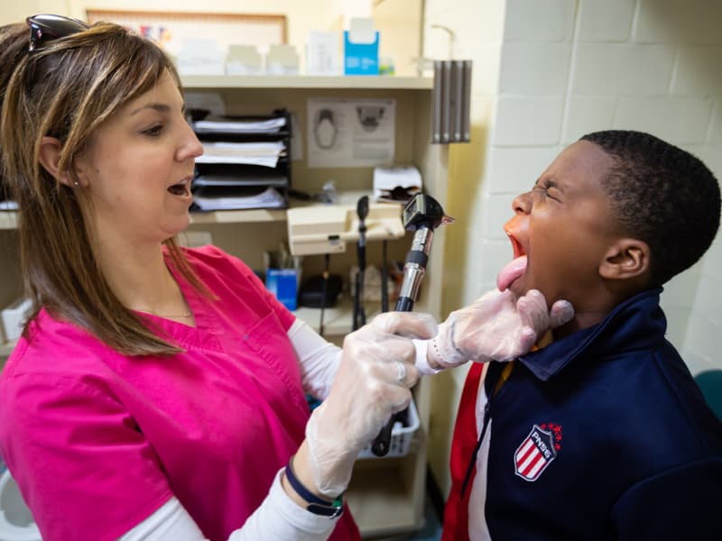 In this March 2019 photo, Gwen Dew, nurse, examines Albert Russell's throat at the school-based clinic at South Delta Middle School.