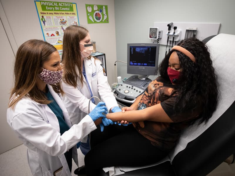 Dr. Nilda Williams, left, UMMC assistant professor of radiology, and Dr. Alyson Stacks Carraway, UMMC radiology resident, scan Da Imesia Adams of Jackson, a patient being evaluated at the Jackson Free Clinic.