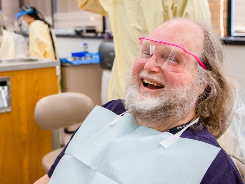 Coleman Williamson of Brandon, a U.S. Air Force veteran, jokes with caregivers in the School of Dentistry clinic during Dental Mission Week.