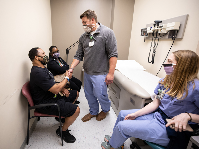 COVID-19 survivor Derek Carter Sr. shakes the hand of registered nurse Matt Harris, center, who with RN Lauren Boler, right, took care of Carter for many weeks in UMMC's Medical ICU. With Carter is his wife, Elizabeth McCray-Carter.