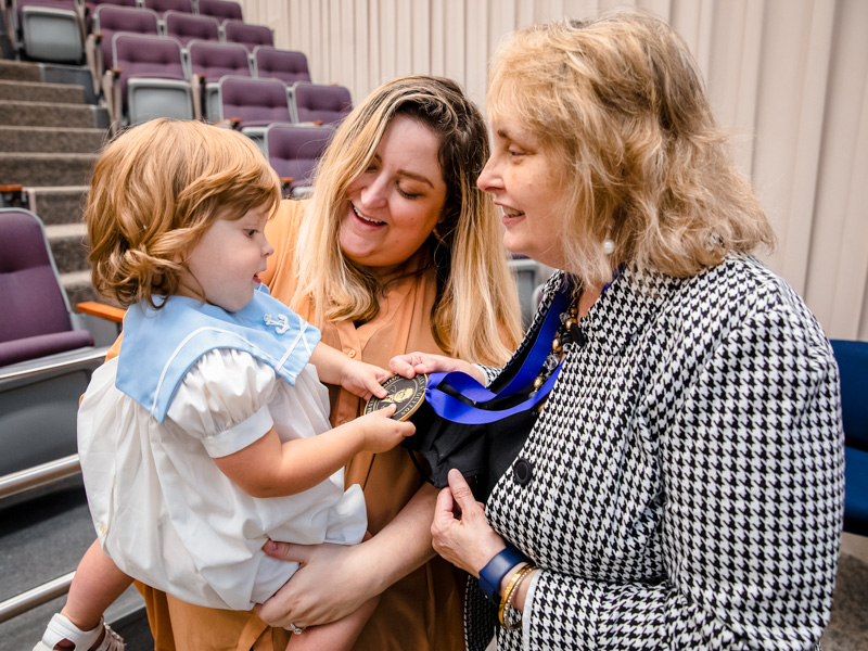 Elizabeth Padgett, granddaughter, and her mom DeBow Alexander Padgett check out the medallion presented Dr. Barbara Alexander who was recognized as a Billy S. Guyton Distinguished Professor.