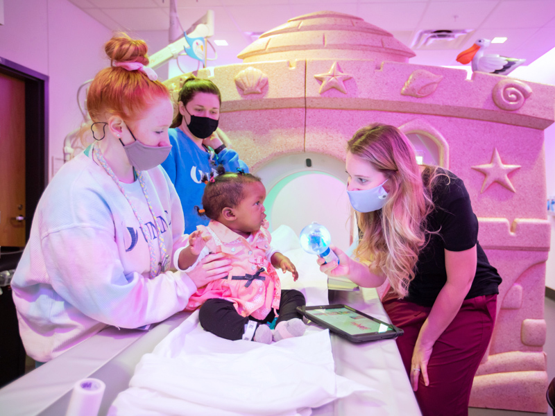 Child life specialist Madeline Wilson talks with patient Bethany Jackson of Woodville. Calming children as young as toddlers like Bethany reduces the need for sedation in imaging. With her are CT technologists Madilynn Tarver, left, and Amber Jelen.