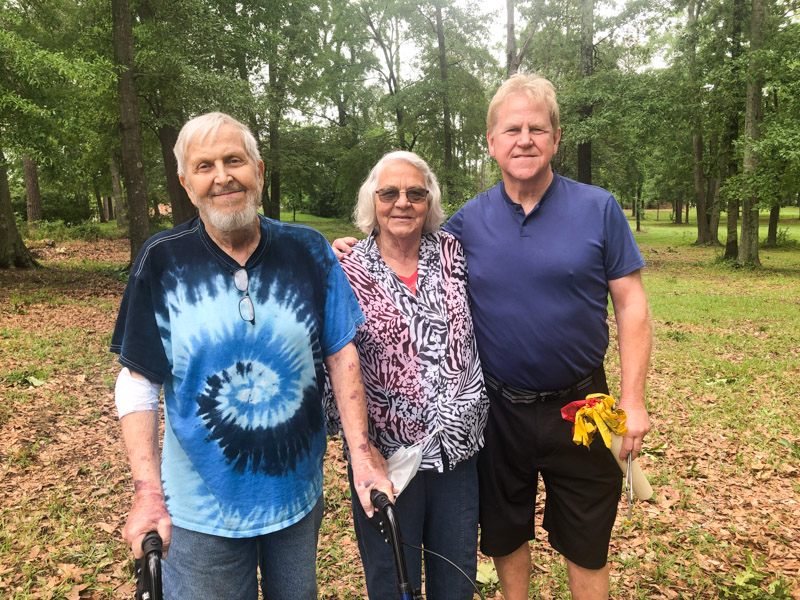 Siblings, from left, James T. Lee and Suzy Morris, both of Owensboro, Kentucky, and Wayne Lee of Durham, North Carolina, pay tribute to the memory of their grandfather, John B. Whitfill, or Whitfield, who was buried in the Asylum Cemetery in January of 1932. The siblings visited the Medical Center in May.