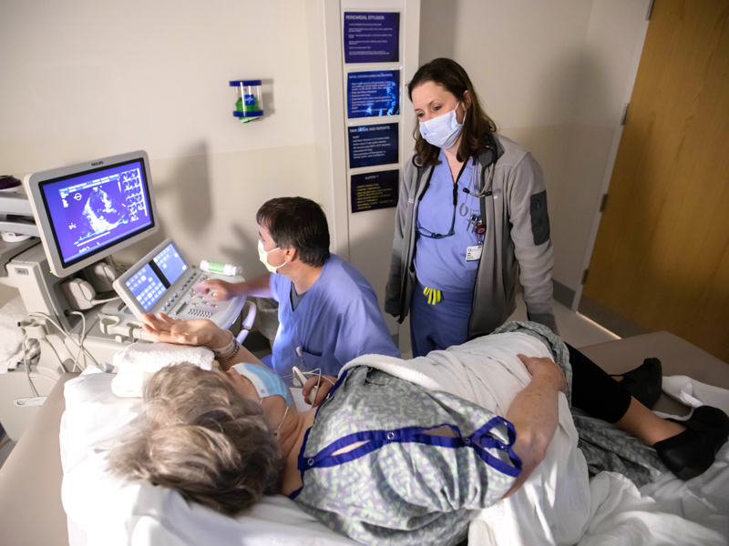 Dr. Kellan Ashley talks with Betty Bishop, a TAVR patient, while Karol Black, a diagnostic sonographer, performs an echocardiogram during a June 4 follow-up visit.