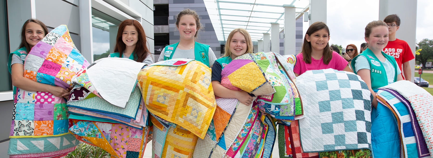 Holding armloads of handmade quilts for babies in neonatal intensive care, Girl Scouts in Troop 3965 include, from left, Zoey Dowdy, Presleigh Stigler, Nichole Johnson, Maggie Josey, Ellie Kegley and Katey Rae Quick.