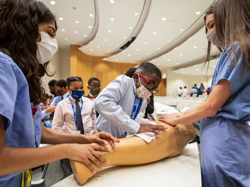 Davis Dorsey learns how to perform wound care with Tracy Rappai, left, and Kinsley Stuart, second-year medical students, during the Black Men in Healthcare Empowerment Summit June 26 in the medical education building.