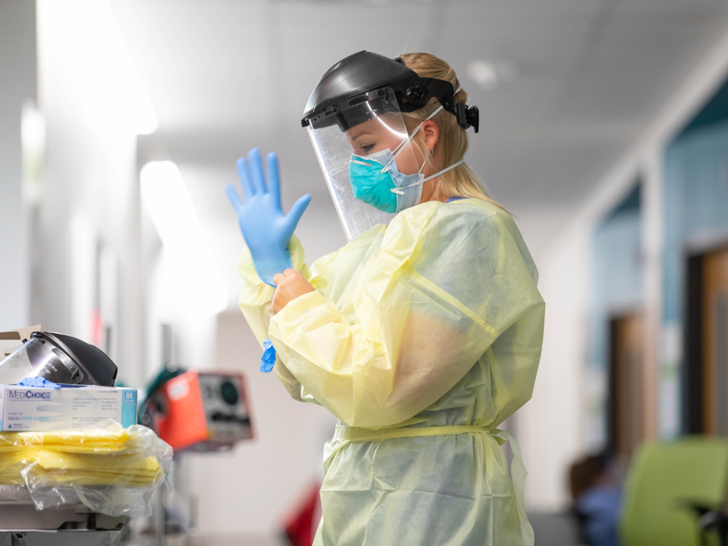 Infectious disease nurse practitioner Spencer Brooks puts on personal protective equipment before checking on a COVID-19 patient in pediatric intensive care at Children's of Mississippi.