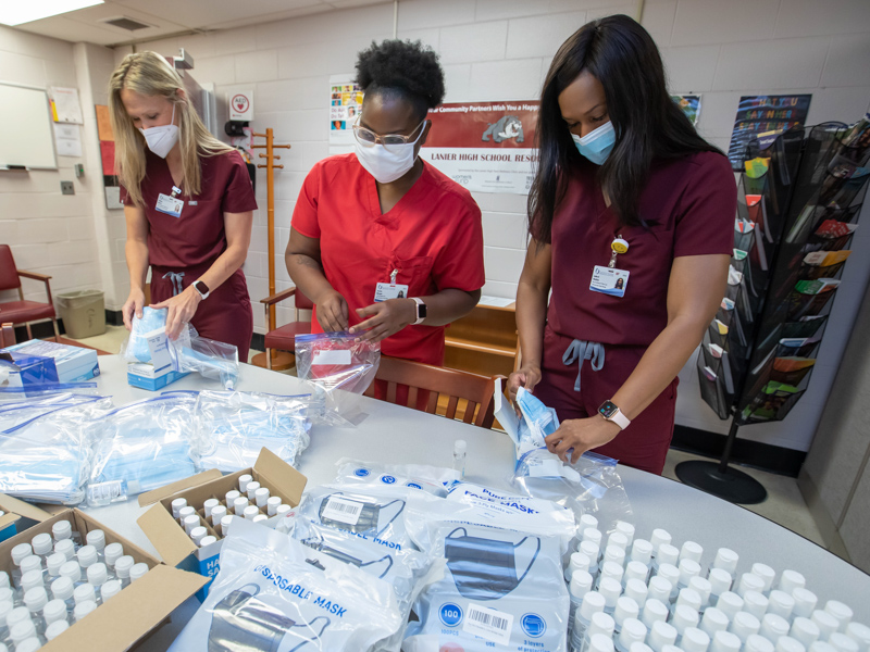 Staff from the Lanier Teen Wellness Clinic, including from left,  nurse practitioner Valerie Morris, medical assistant Jessica Morgan and nurse practitioner LaDaryl Watkins, unload face masks and bottles of hand sanitizer that were donated by School of Nursing students and faculty and given to families in the community Sunday.