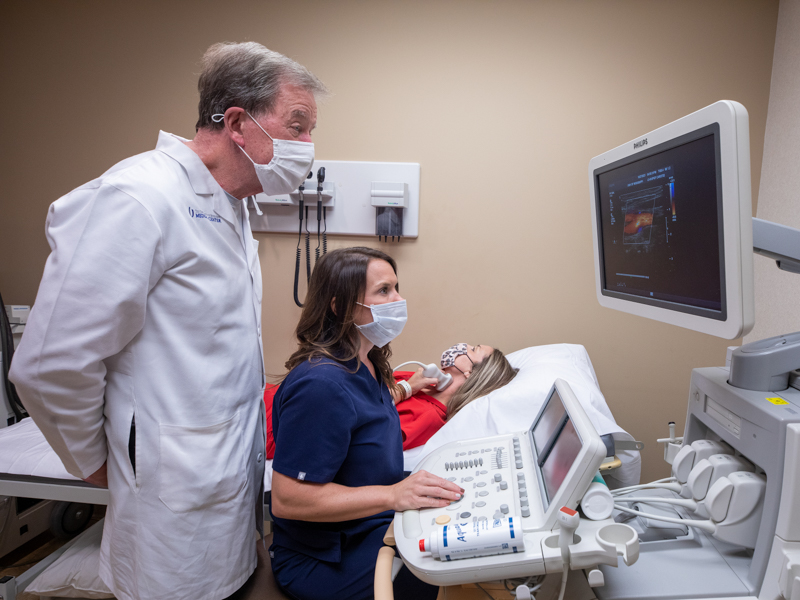 Amanda Howell, a registered diagnostic sonographer and lead technician in cardiology services at UMMC Grants Ferry, performs a cardiac sonogram on a patient as Dr. Bryan Barksdale, a cardiologist and professor in the Division of Cardiovascular Diseases, looks on.
