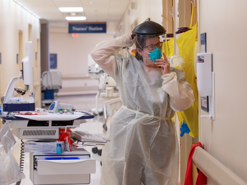 Registered nurse Nicole Winham prepares to enter the hospital floor room of a COVID-19 patient.