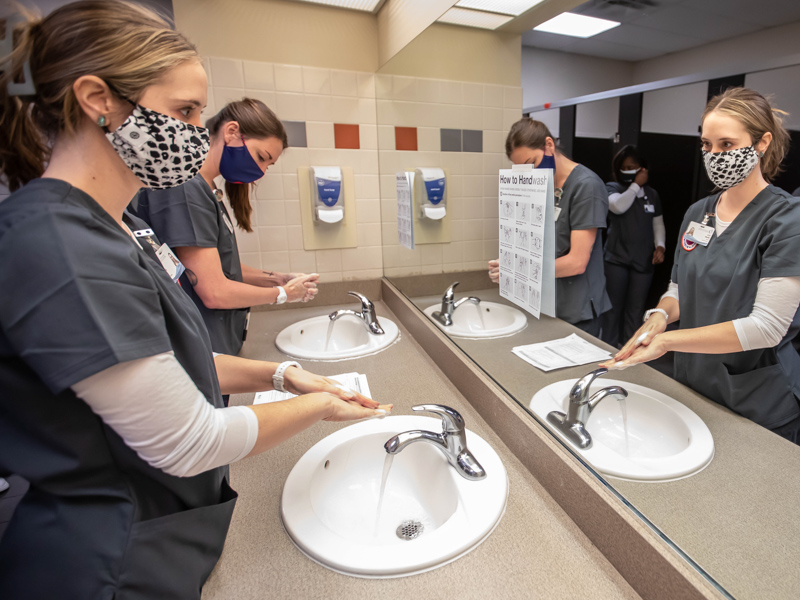 Accelerated BSN students Carrie Gilreath, left, and Jessica Hern follow instructions at the hand-washing station during a skills lab.