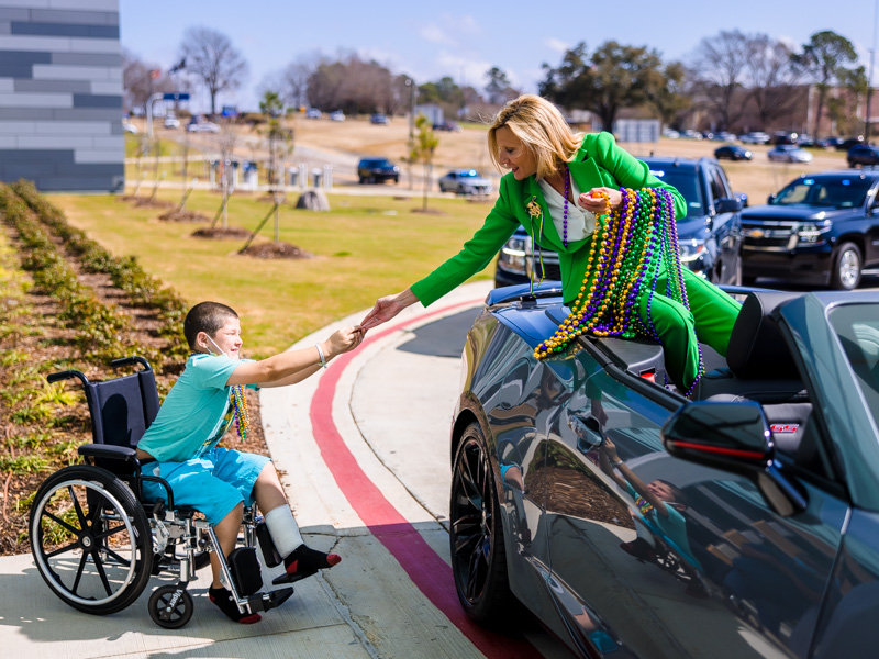 Children's of Mississippi patient Nolan Busby of Oak Grove, Louisiana, reaches to catch a small toy thrown by Mississippi First Lady Elee Reeves during a Department of Public Safety Mardi Gras parade Thursday.