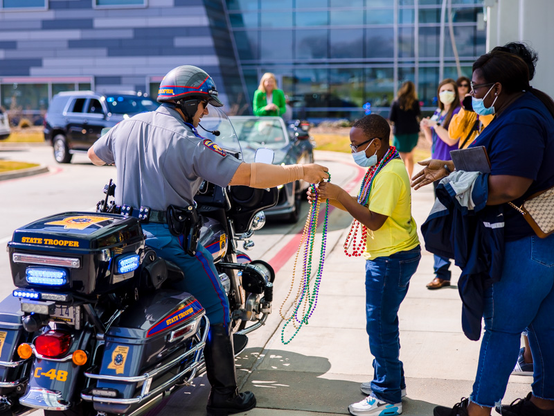 A Mississippi Highway Patrol officer hands Mardi Gras beads to Children's of Mississippi patient Dante Woods of Natchez.
