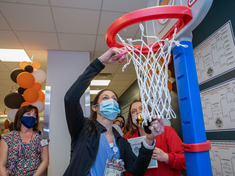 Stephanie Wagner, a registered nurse in Cardiovascular Holding, cuts the net from the basketball goal during the Patient Safety Week awards ceremony. Her department was recognized for having the best patient experience scores for 2021.