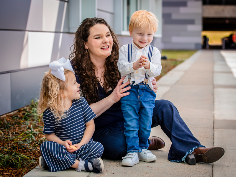 Mom Karinlee Brister smiles with children Kathrynlee and Jackson Brister-McDaniel by the Kathy and Joe Sanderson Tower at Children's of Mississippi.