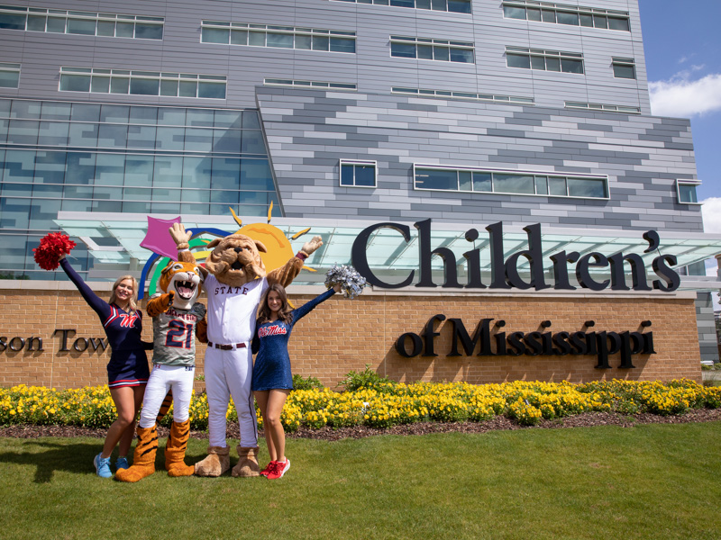 Cheering on patients at Children's of Mississippi are, from left, Ole Miss cheerleader Mara Liston, Jackson State mascot Sonny Thee Tiger, Mississippi State's Bully and Ole Mixx dance team member Jane Granberry. Jay Ferchaud/ UMMC Communications