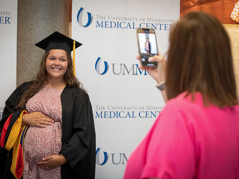 Hannah Brown, who earned a Master of Science degree in Biomedical Sciences, shows her baby bump to mom Sheri for a photo.