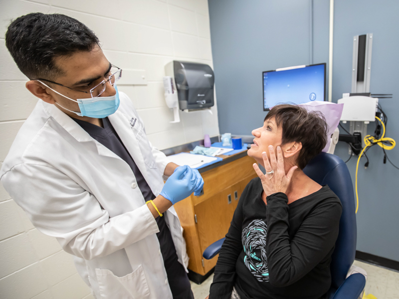 Patient Carol Hoover shows Dr. Rohan Jagtap where her jaw pain is as he examines her following a cone beam CT scan at the School of Dentistry. MT