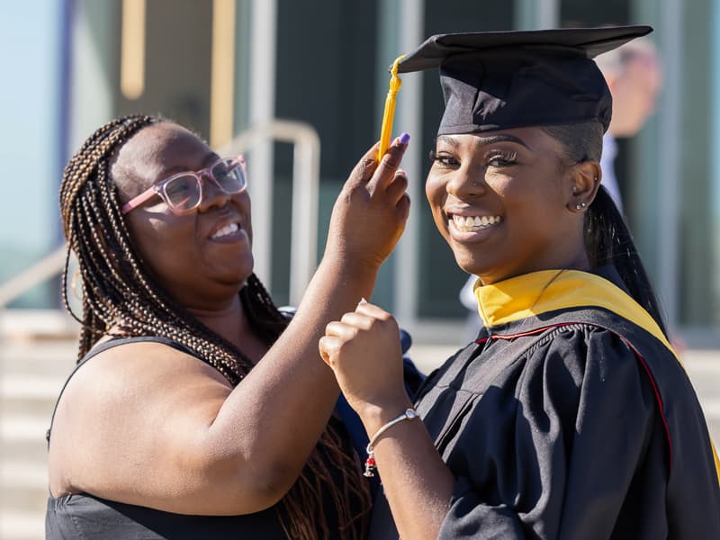 Pamela Williams helps daughter Hailey Jackson, a Master of Science in Biomedical Sciences graduate, with her cap prior to commencement ceremonies.