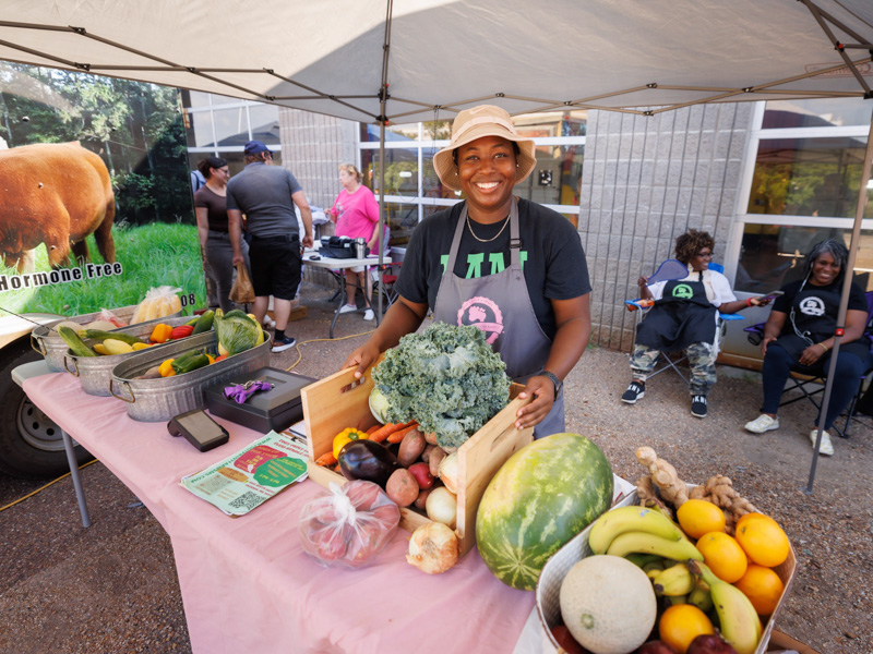 Michel'le Wheatley of Foot Print Farms in Jackson shows off an abundance of fresh vegetables for sale at Thursday afternoon's farmer's Market behind Backyard Burger. The event was sponsored by the UMMC Office of Well-being. Joe Ellis/ UMMC Communications 