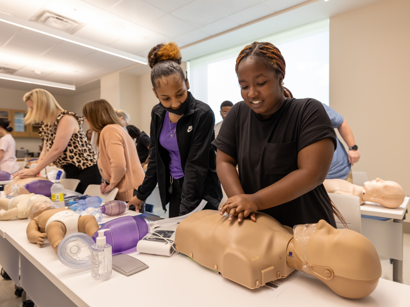 North Pike High School's Ashley Hodges, right, and Cerigan Belle, a student at Aberdeen High, practice chest compressions during Basic Life Support Training for the July session of Mosaic.