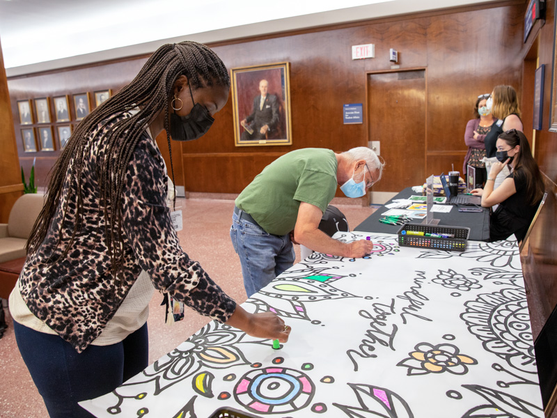 Iesha Smith and Dr. David Brown use paint sticks to add their contributions to a collaborative art project that will hang in the hospital. Jay Ferchaud/ UMMC Communications