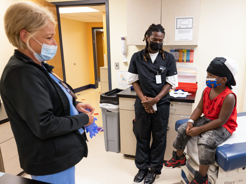 Nurse Kristi Chambley talks with Roderick Everett before giving him his COVID-19 vaccination as dad Roderick Smith looks on. Melanie Thortis/ UMMC Communications 