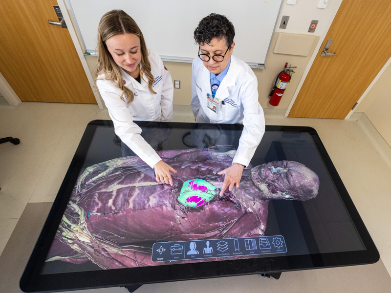 Dr. Norma Ojeda, right demonstrates 3D-virtual cadaver dissection technology to Casey Marie Boothe, a student in the School of Graduate Studies in Health Sciences. Jay Ferchaud/ UMMC Communications