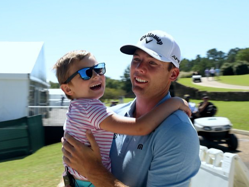 Mary Mosley smiles while being carried by PGA golfer Sam Burns during a visit to the Sanderson Farms Championship.