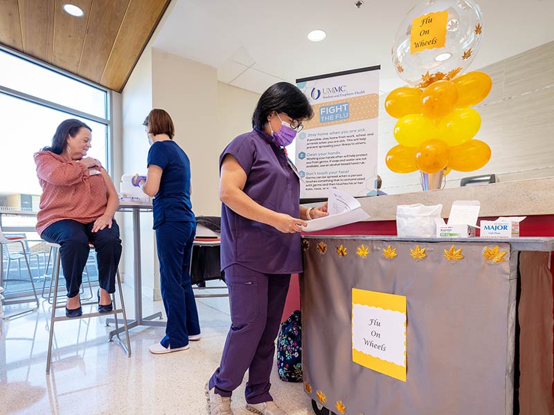 Mayeth Alkuino, right, positions the Flu on Wheels cart in the Translational Research Center.