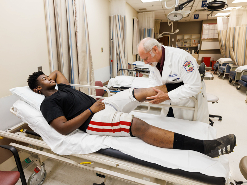 Dr. William Geissler checks the knee of Provine High football player Brian Washington during the Friday night clinic. Joe Ellis/ UMMC Communications