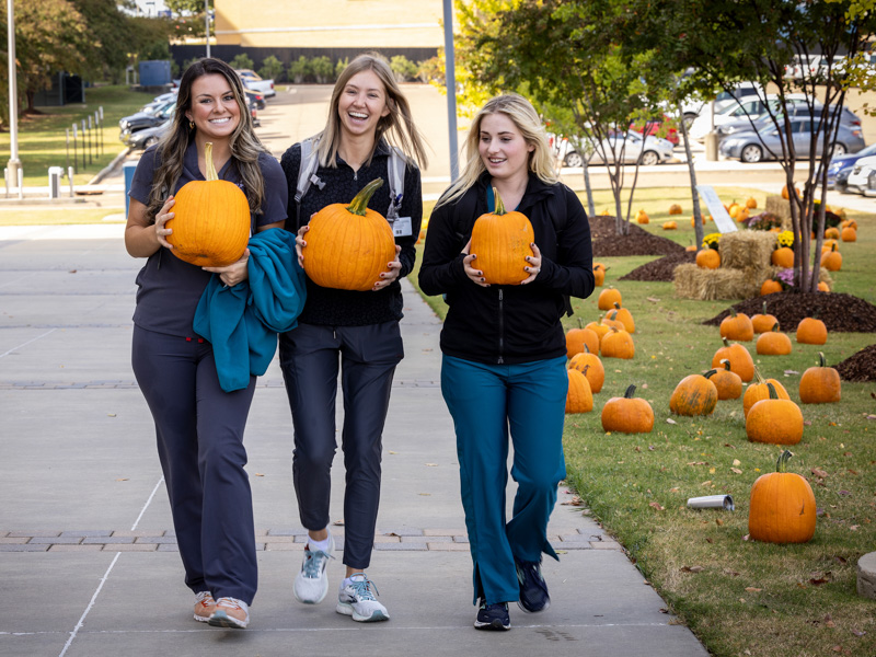 Dental students, from left, Bayley Graves and Tamara Vajanovic and Kennedi Pass of the School of Graduate Studies pick their pumpkins. Jay Ferchaud/ UMMC Communications 