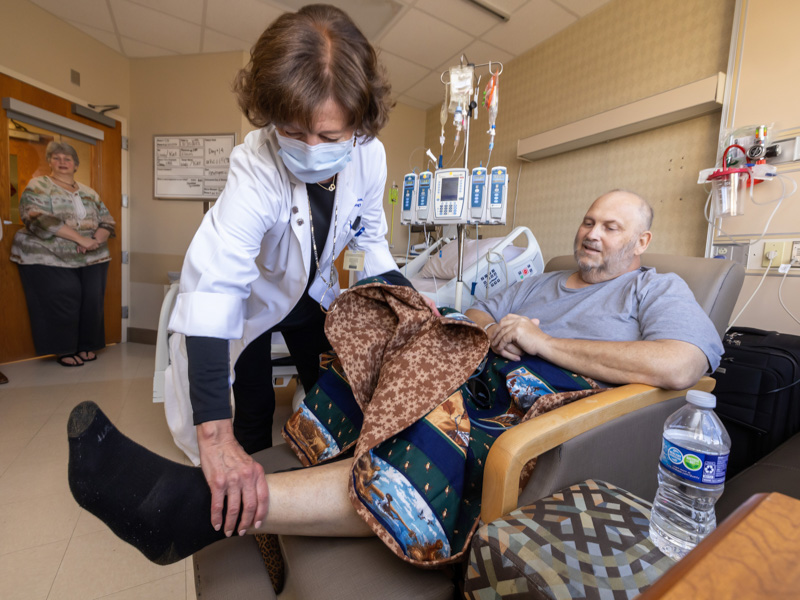 Dr. Carolyn Bigelow, left, looks at the legs of BMT patient Scott Brumfield of Fayette to check for any side effects or infections following his transplant. Jay Ferchaud/ UMMC Communications