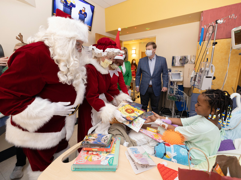 Santa, Mrs. Claus, an elf, First Lady of Mississippi Elee Reeves and Gov. Tate Reeves pass presents to Children's of Mississippi patient Zoie Ward of Jackson. Jay Ferchaud/ UMMC Communications 