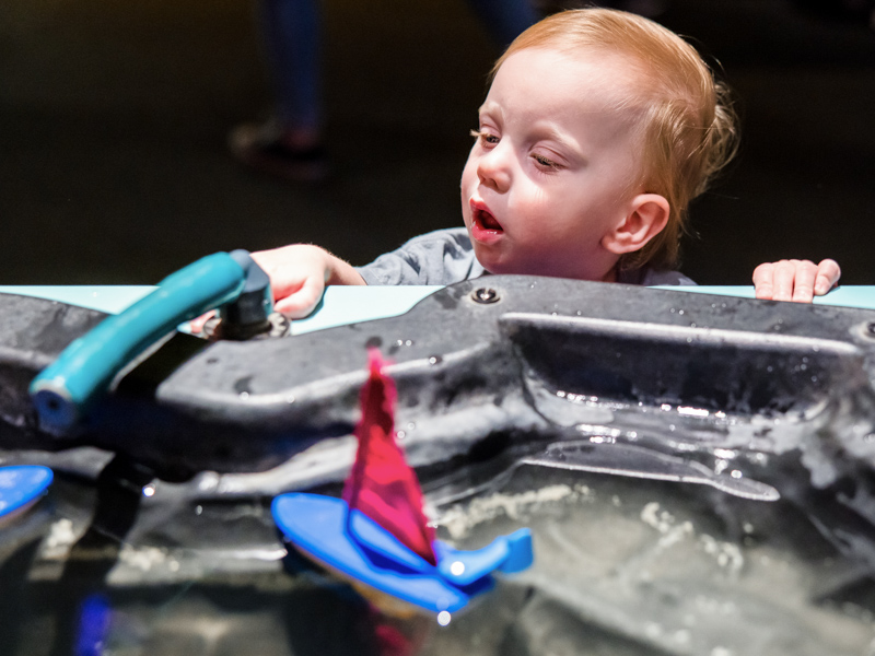 Children's of Mississippi patient Keaton Lazurus watches toy boats float by in an exhibit at the Mississippi Museum of Natural Science.