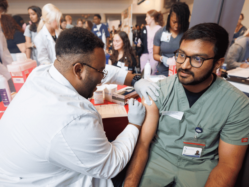 Occupational Therapy student Tejay Patel, right, receives his flu vaccine from Pharmacy student Tyler Fuller during the IPE Block Party at the Student Union.