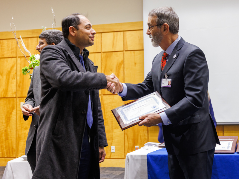 Academy inductee Dr. Saurabh Bhardwaj, left, associate professor of psychiatry, accepts his certificate and congratulations from fellow academy initiate, Dr. Rob Rockhold, professor emeritus of pharmacology/toxicology and chair of the academy's membership committee.