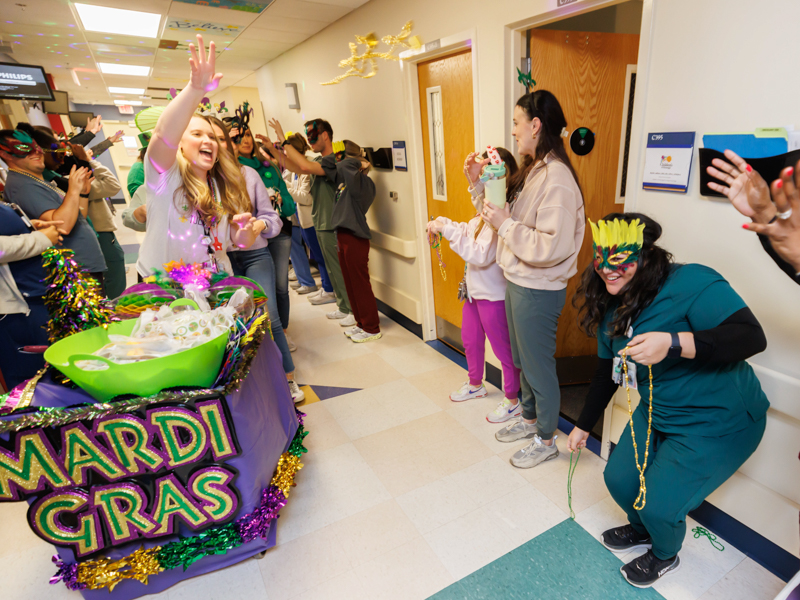 Child life specialist Madeline Wilson tosses beads during a Mardi Gras parade on Fat Tuesday. Melanie Thortis/ UMMC Photography 