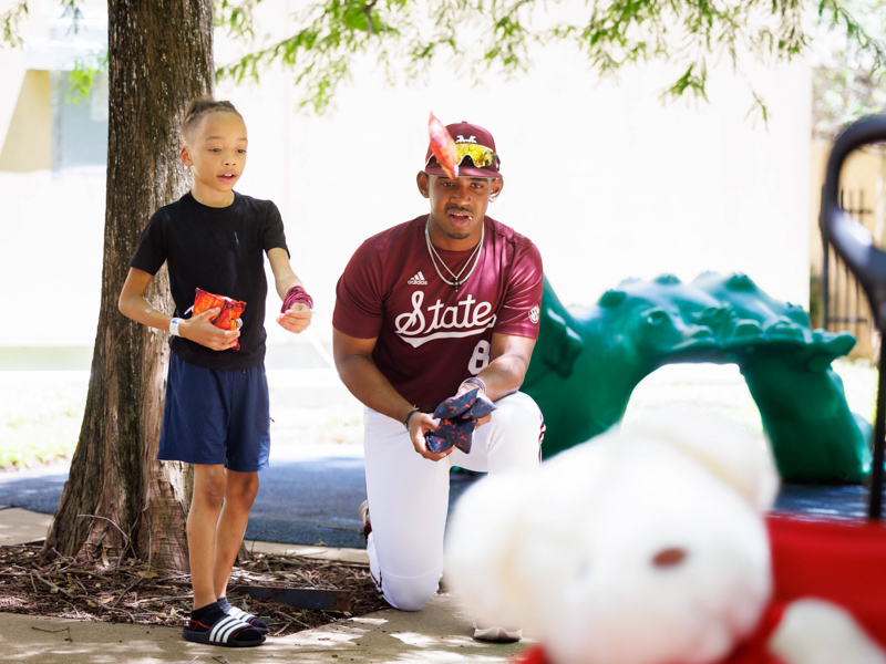 Ayden Demus, of Vaughan, a patient at Children's of Mississippi, tosses some beanbags with MSU infielder Amani Larry.