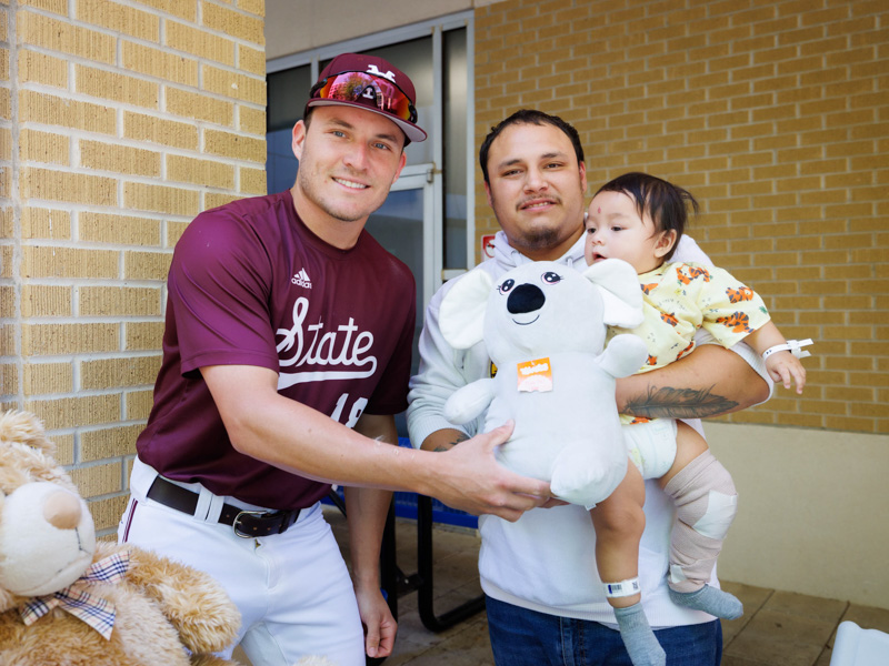 MSU catcher Johnny Long poses with a stuffed toy with Serenity Charlie, of Philadelphia, a patient at Children's of Mississippi and her dad.